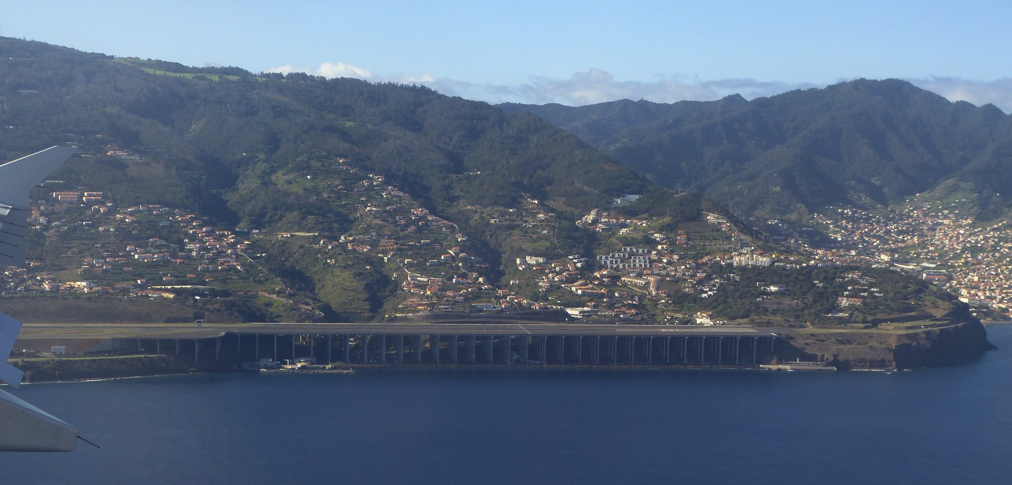 The approach to Madeira airport seen from a window seat, the runway on its pillars along the coast