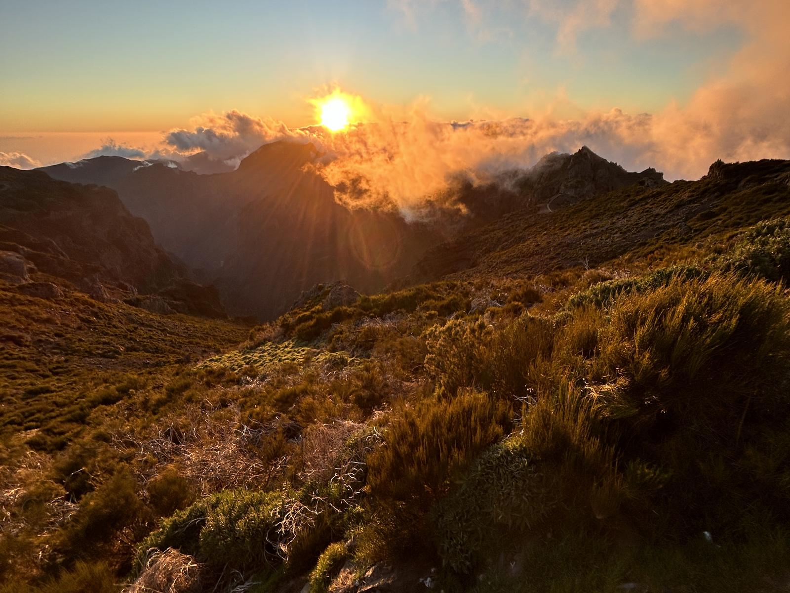 The sun going down over the peaks at Pico do Arieiro, cloud glowing along the ridges and the heather lit gold