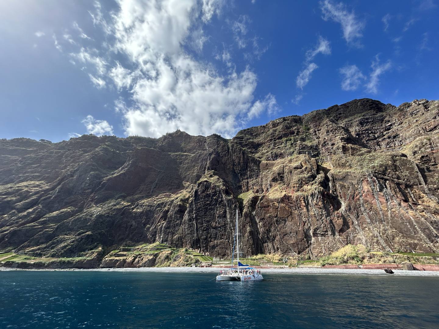 The Cabo Girão cliff seen from the sea, a catamaran anchored below it