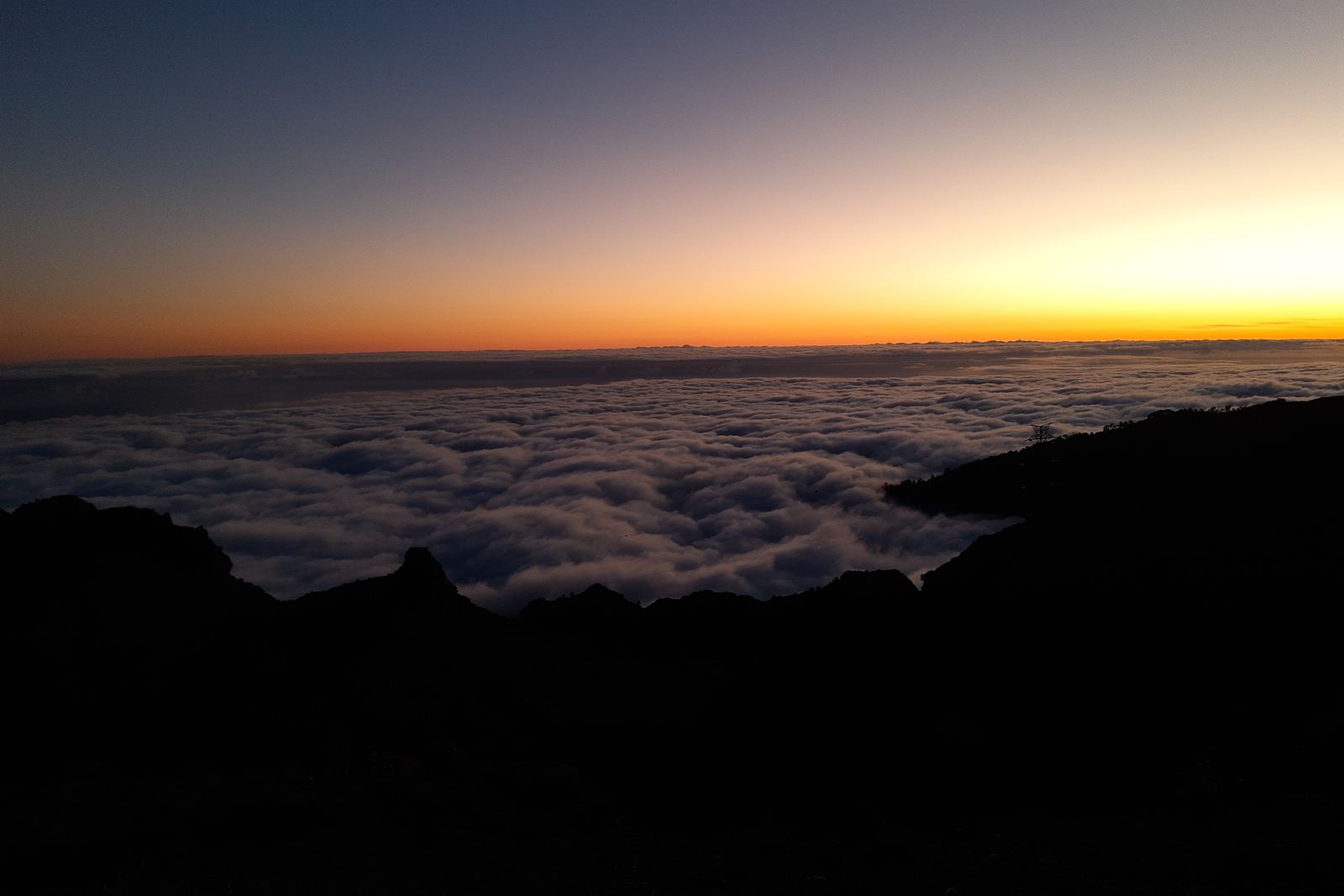 The sky glowing orange after sunset above a sea of cloud, seen from Paul da Serra