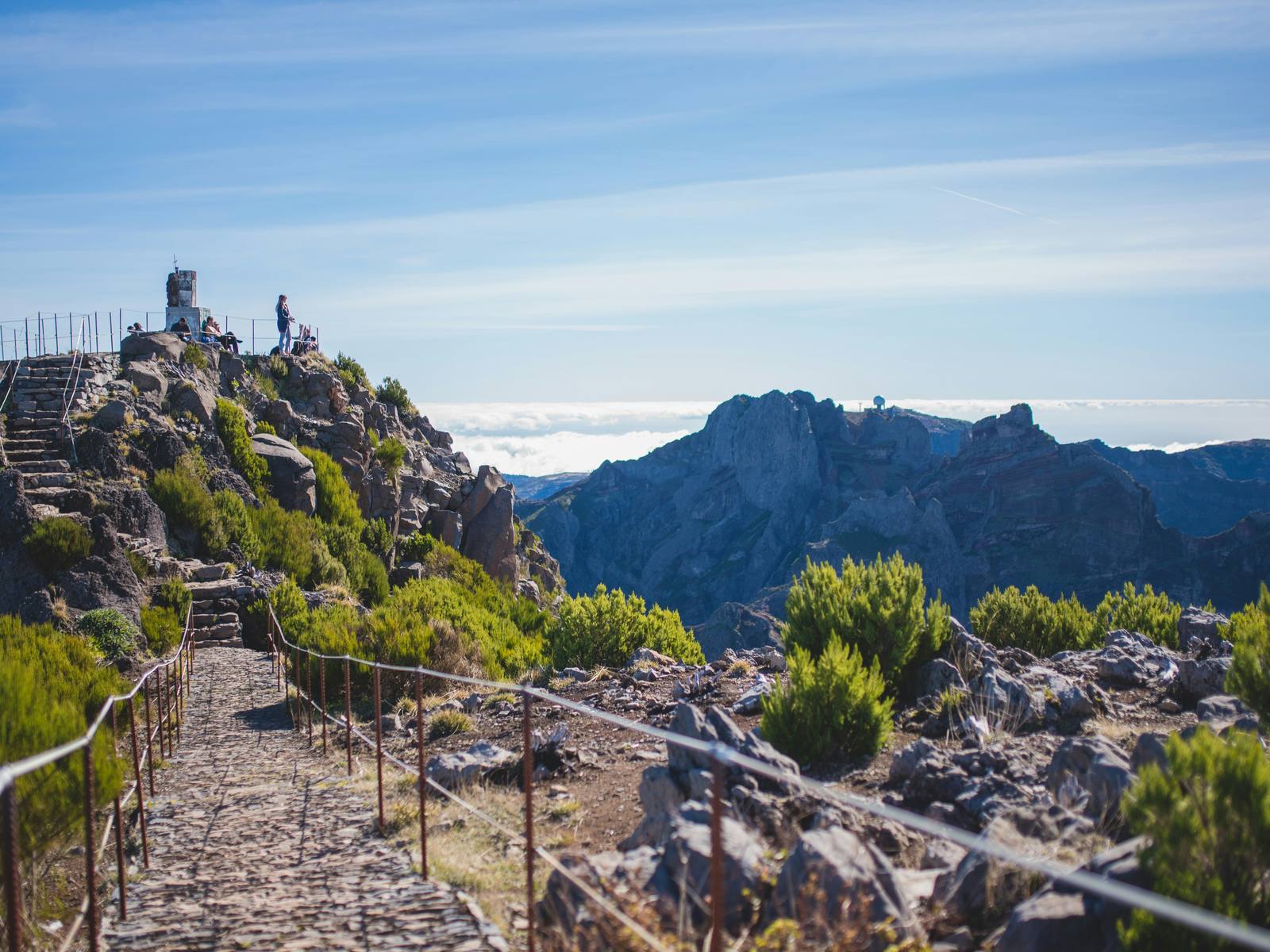 The stone path with railings climbing to the summit of Pico Ruivo, the central peaks and a sea of cloud beyond