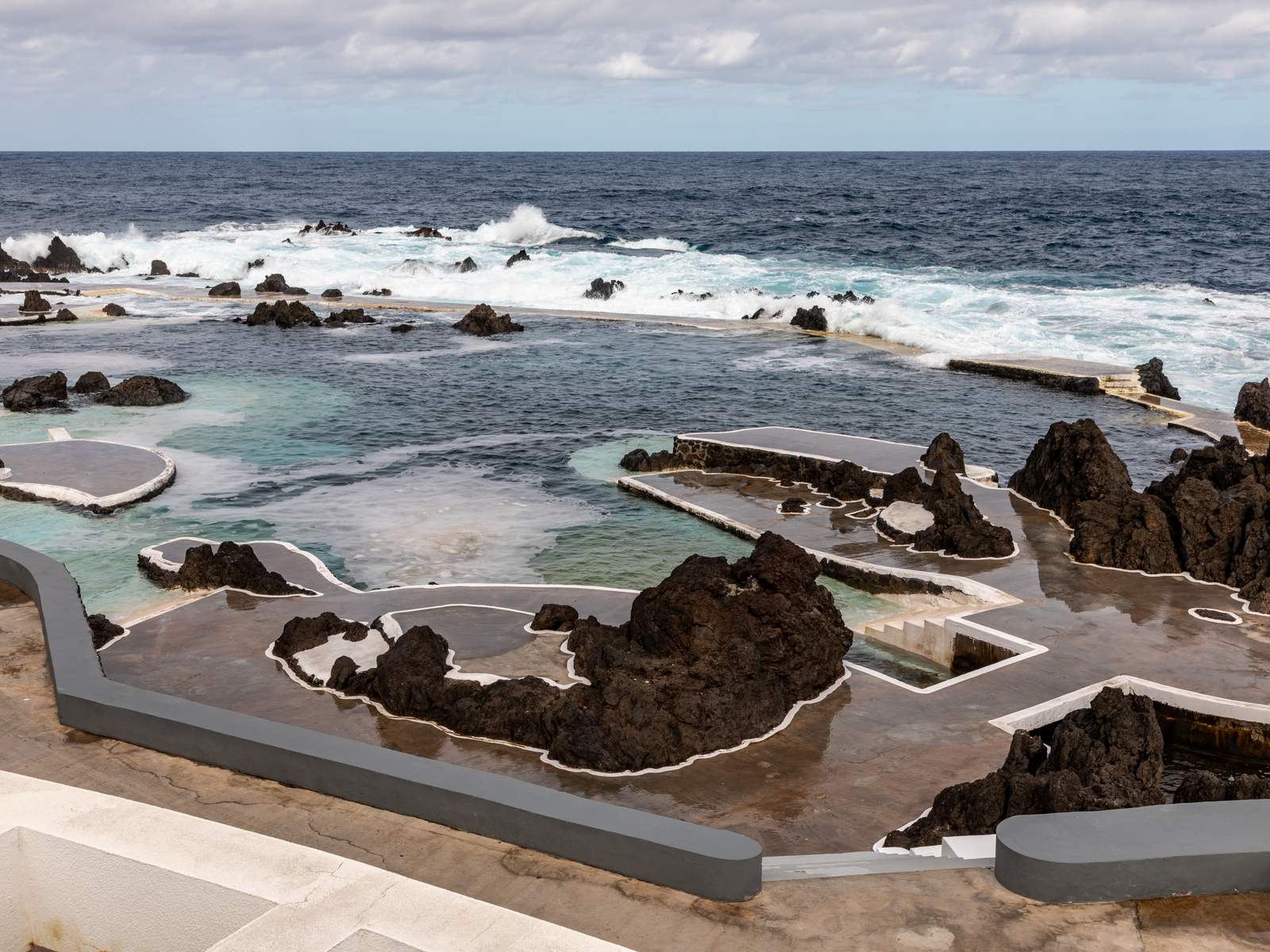 The Porto Moniz sea pools among black lava rocks, Atlantic waves breaking over the outer rocks