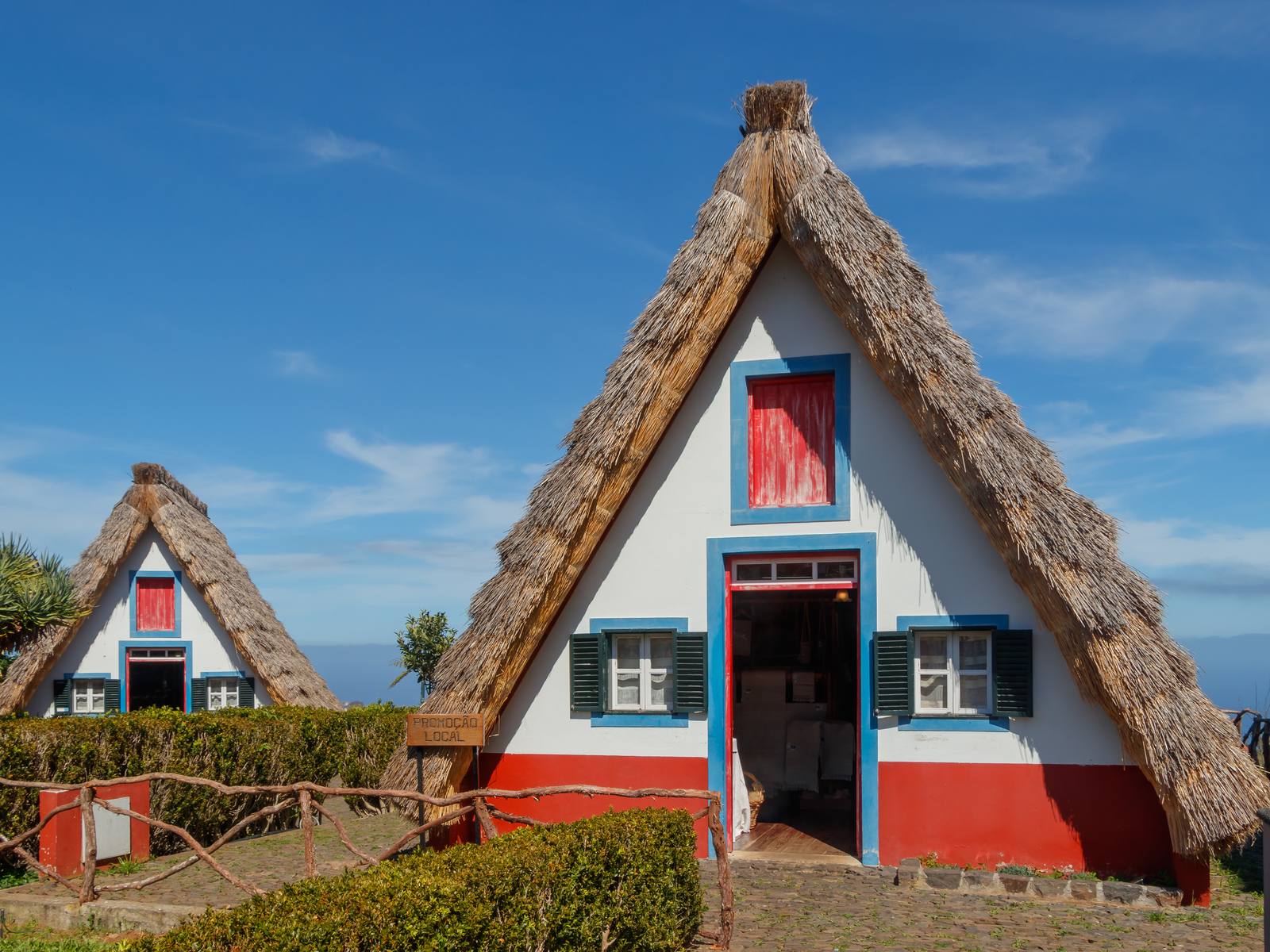 Two thatched A-frame houses in Santana with red doors, blue trim and green shutters