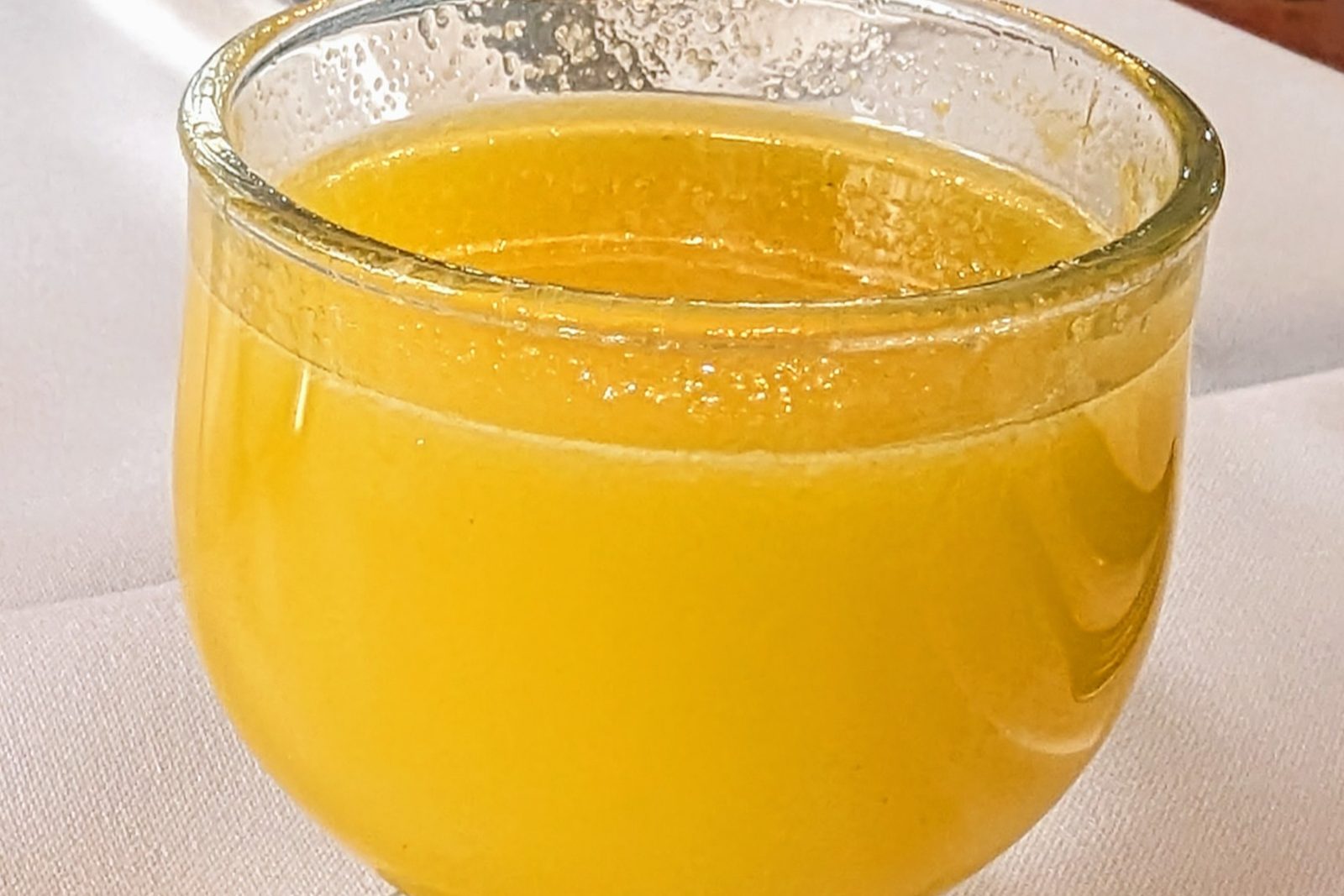 A glass of yellow poncha on a white tablecloth