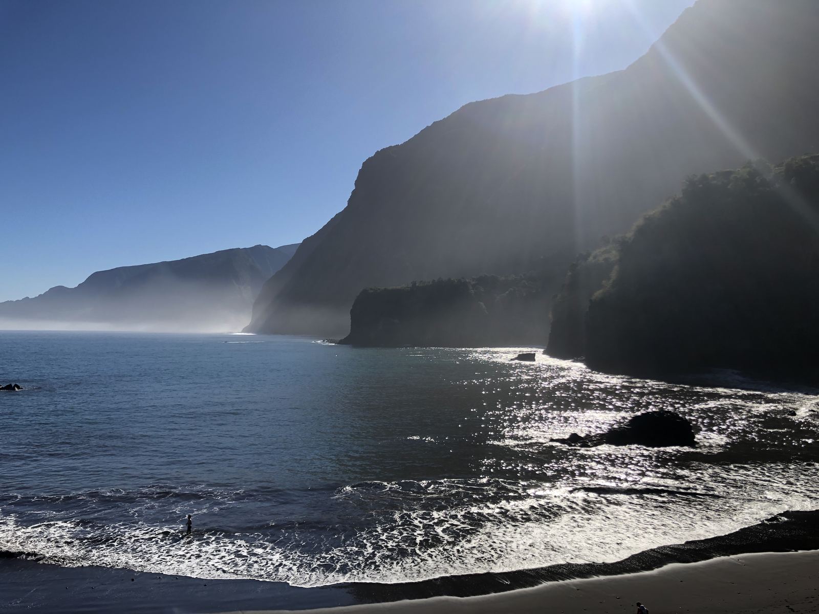 Waves running up the black sand beach at Seixal under the north coast cliffs